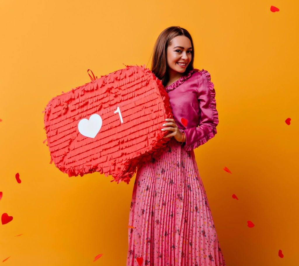 gorgeous joyful cheerful girl posing with red decorations her hands portrait brown haired woman pink outfit against wall confetti shape hearts