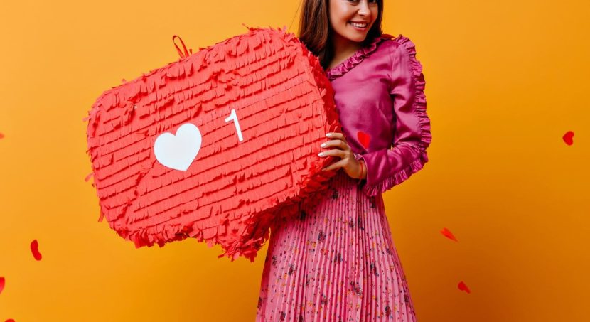 gorgeous joyful cheerful girl posing with red decorations her hands portrait brown haired woman pink outfit against wall confetti shape hearts